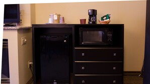 Una kitchenette compacta equipada con microondas, cafetera y un refrigerador pequeño.