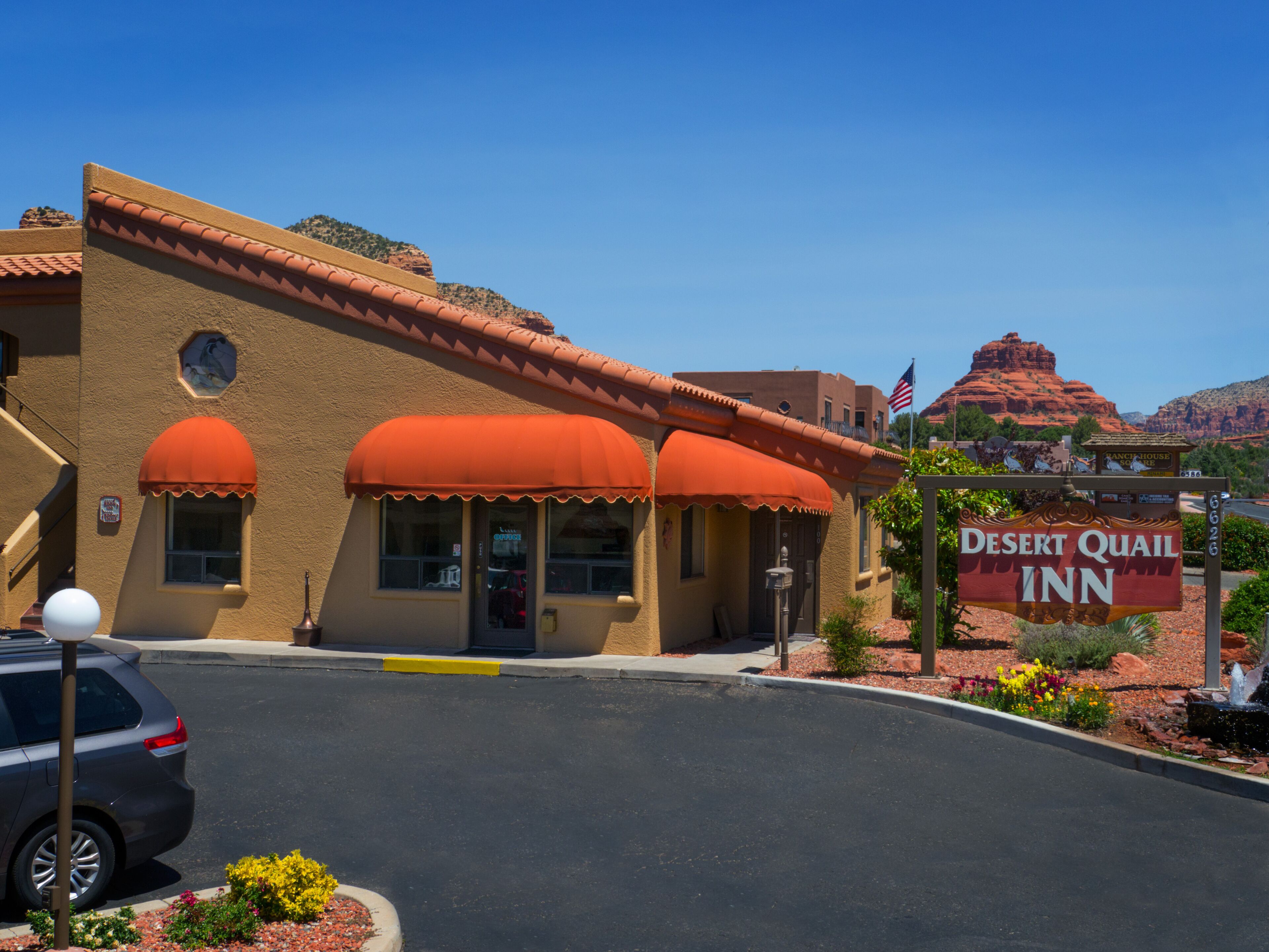 A Desert Quail Inn with a red awning, a visible American flag, and a signboard.