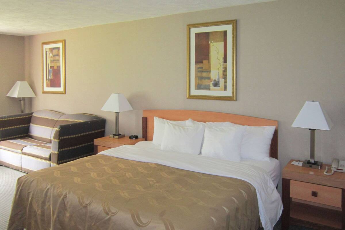 A hotel room with a bed, two bedside tables, a chair, and two lamps.