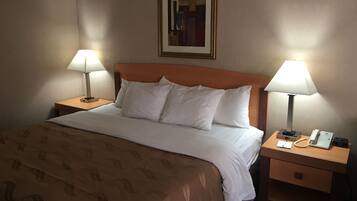 Una habitación de hotel con cama, dos mesitas de noche, un teléfono y un cuadro en la pared.
