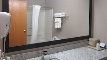 A bathroom with a granite countertop, a sink, a mirror, a towel rack, and a door.