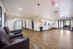 Una habitación amplia con suelo de madera, mostrador de recepción y zona de estar con sillas.