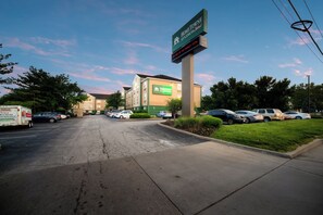 A parking lot with a building labeled 'Home Town Studios' in the background. - HomeTowne Studios by Red Roof St. Louis - Airport/ N Lindbergh (Hazelwood)