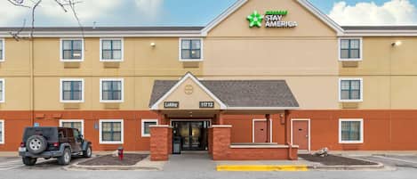 A hotel with a yellow facade, a green logo, and a sign indicating a lobby at 11712.