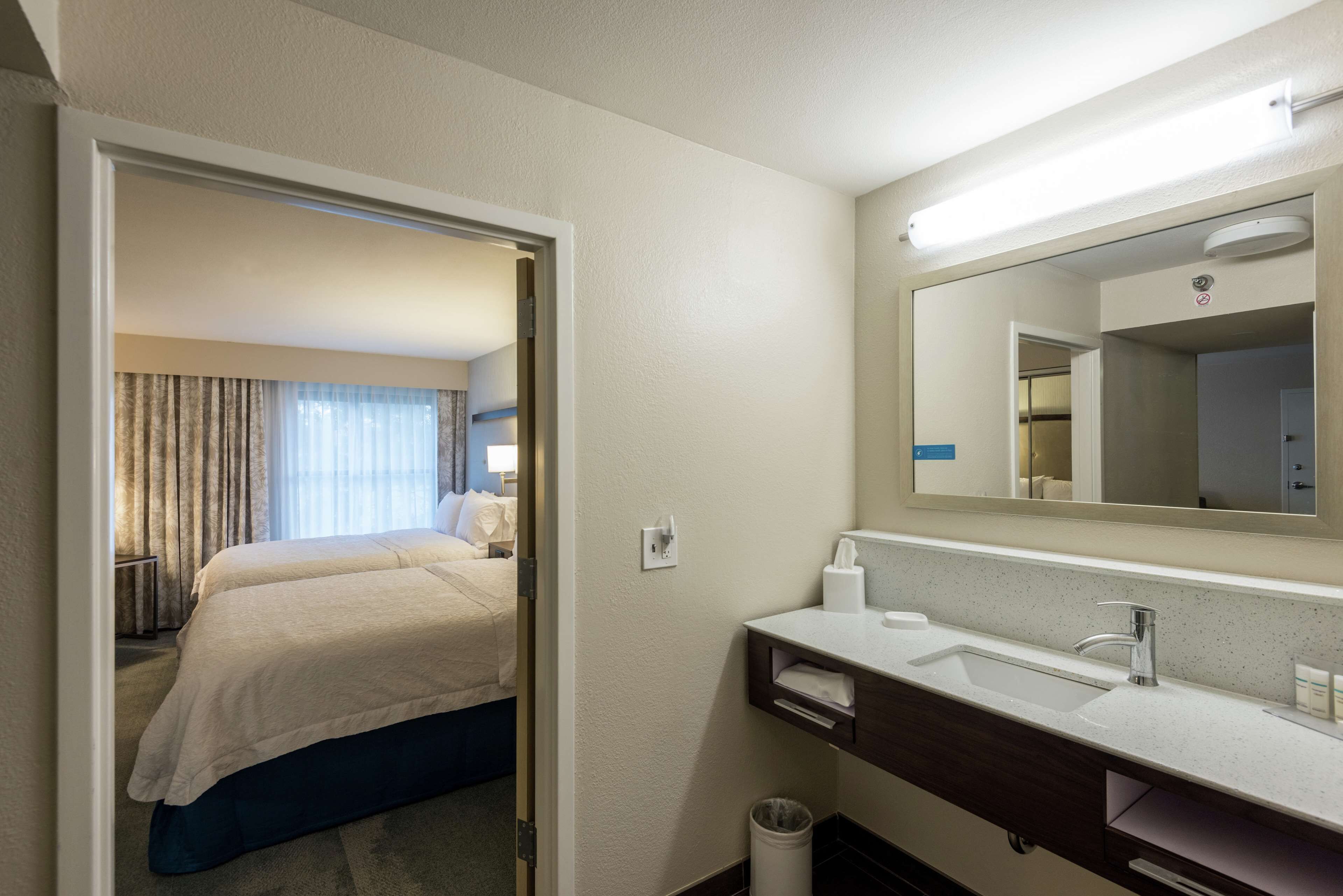 Une chambre d’hôtel avec un lit, une salle de bain avec un lavabo et un miroir.