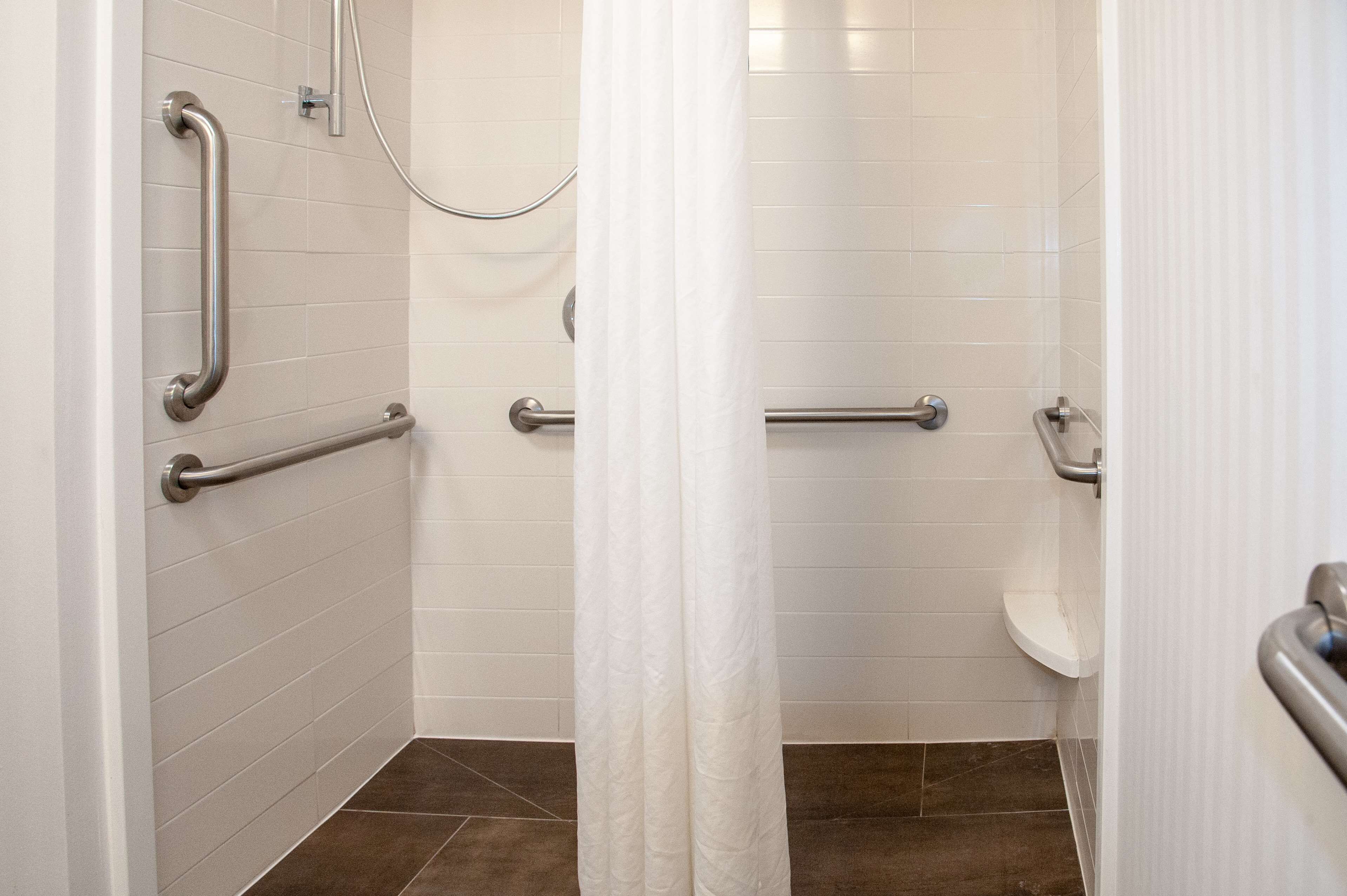 Une salle de bain avec des murs carrelés de blanc, des toilettes blanches et un espace douche.