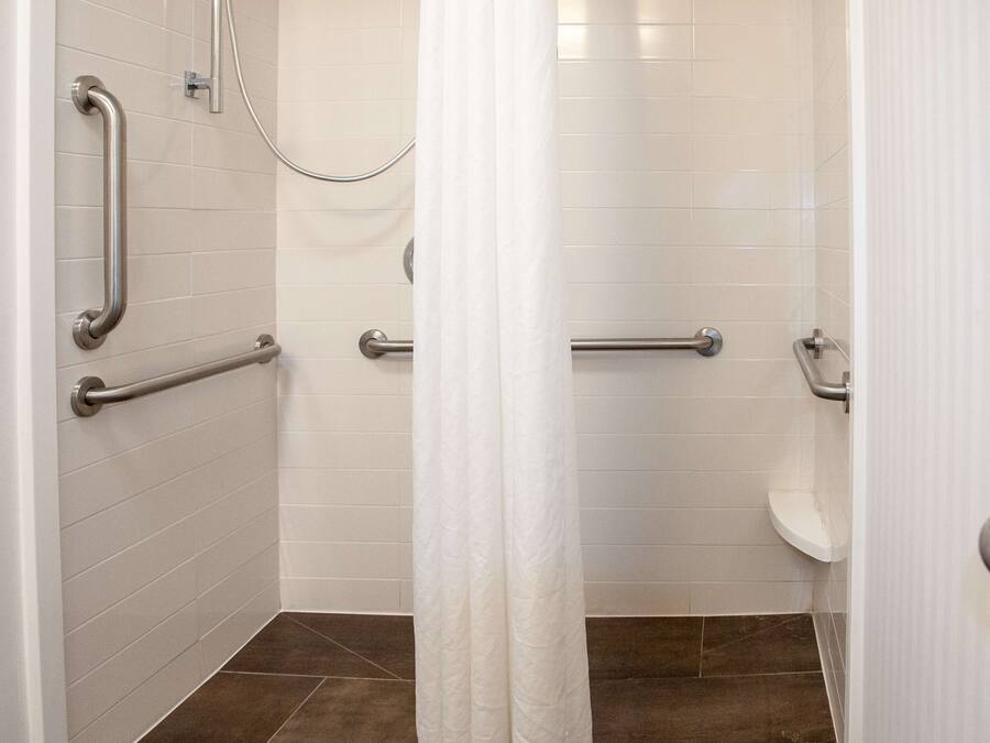Een badkamer met witte betegelde wanden, een wit toilet en een douchehoek.