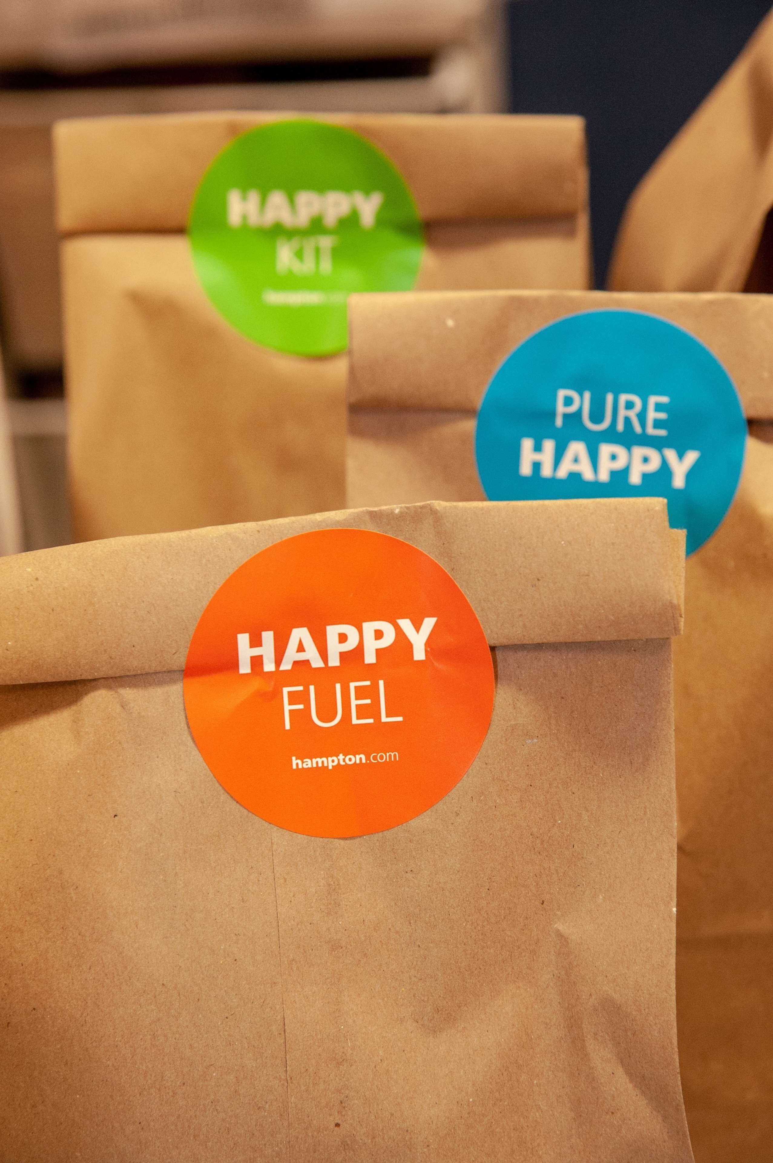 Several brown paper bags with stickers labeled "HAPPY KIT" and "PURE HAPPY".