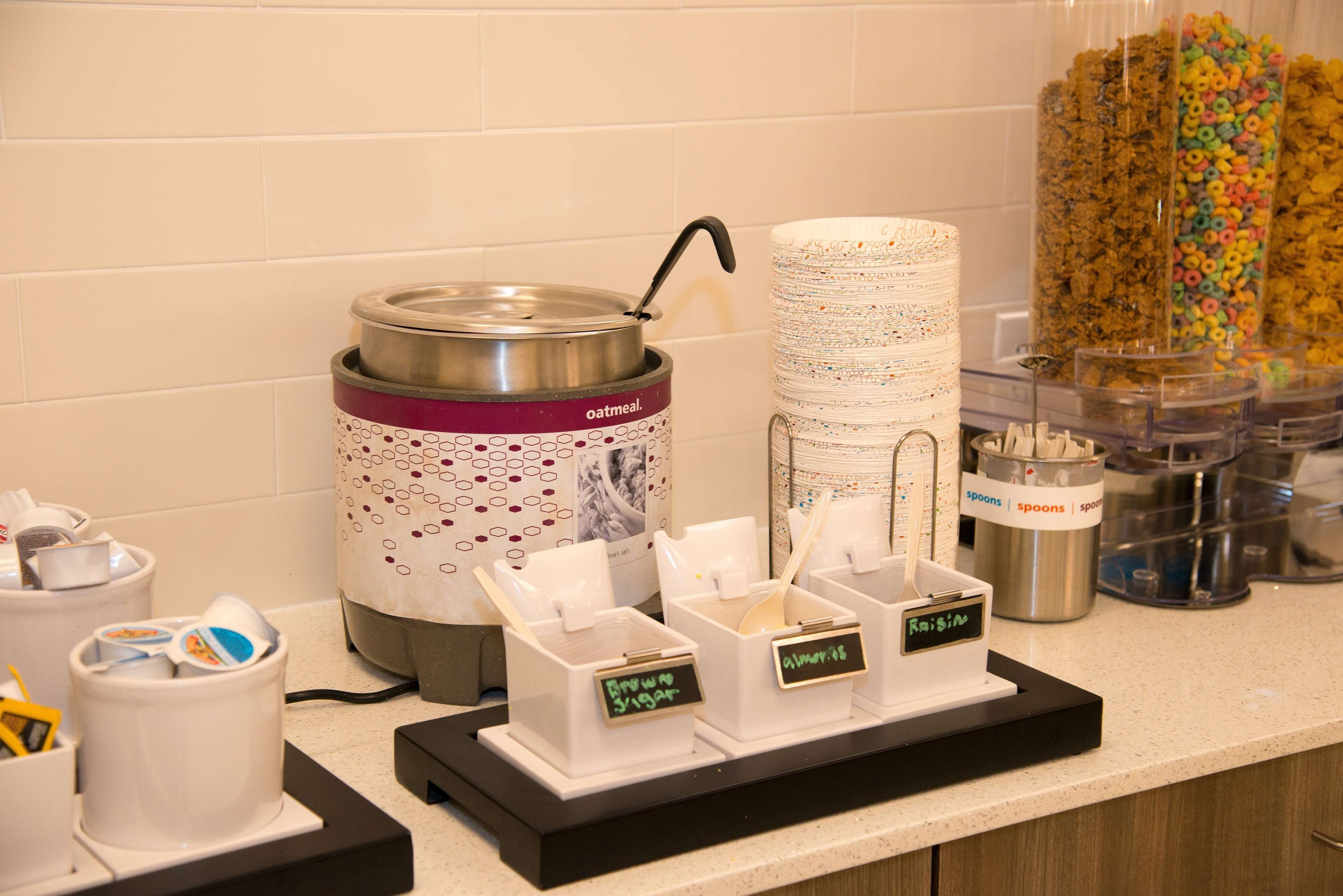 A breakfast station with a coffee maker, sugar and cream dispensers, and a cereal dispenser.