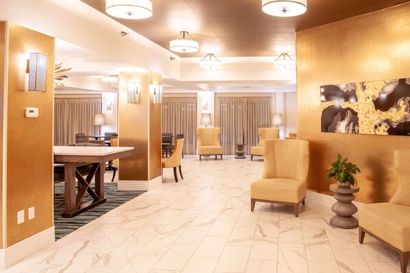 Un vestíbulo de hotel con piso de mármol, una recepción y zonas de estar.
