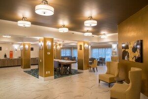 Un amplio vestíbulo de hotel con suelo de mármol, un mostrador de recepción, un comedor y varias opciones de asiento.