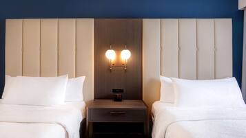 Een hotelkamer met twee bedden, een houten hoofdbord, nachtkastjes met lampen en een digitale klok.