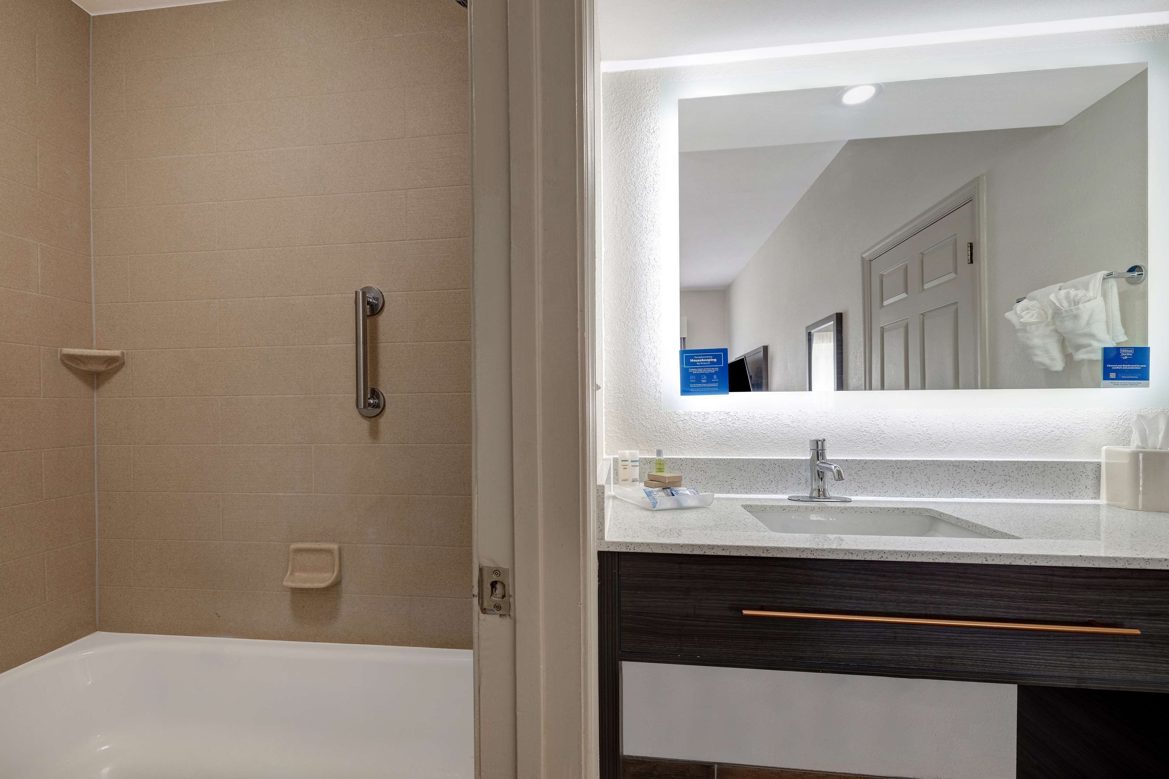 Ein modernes Badezimmer mit einer Badewanne, einem Waschbecken und einem Spiegel.