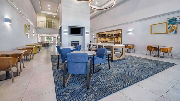 Um hall de hotel moderno com área de estar central, lareira e bar.
