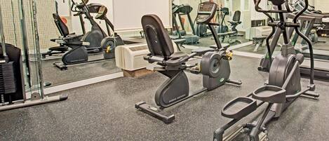 Une salle de sport équipée de divers appareils d’exercice, notamment des tapis de course et des appareils de musculation elliptique.