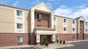 A multi-story hotel with a beige and red facade, numbered 780, featuring a central entrance with a covered walkway and small landscaped areas. - MainStay Suites Omaha Old Mill (Omaha)