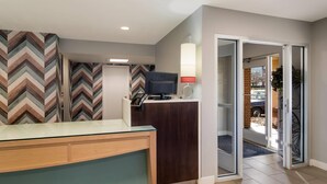 A hotel reception area with a modern desk, a television, and a patterned wall. - MainStay Suites Omaha Old Mill (Omaha)