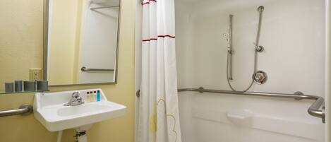 Une salle de bain avec un lavabo blanc, un miroir et une douche avec un rideau blanc.