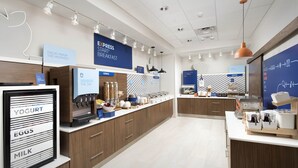 A modern breakfast area with a counter displaying various food items and a sign indicating a breakfast service. - Holiday Inn Express & Suites Central Omaha by IHG (Omaha)