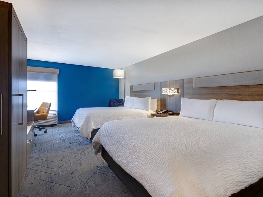 Habitación de hotel con dos camas, un escritorio y una silla.