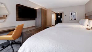 A hotel room with a bed, a desk, a chair, a TV, and a door leading to another room. - Holiday Inn Express & Suites Central Omaha by IHG (Omaha)