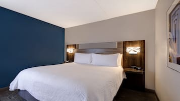 Ett hotellrum med en stor säng, två sängbord och väggmonterad belysning.