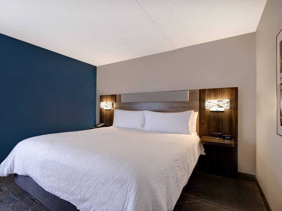 Ett hotellrum med en stor säng, två sängbord och väggmonterad belysning.