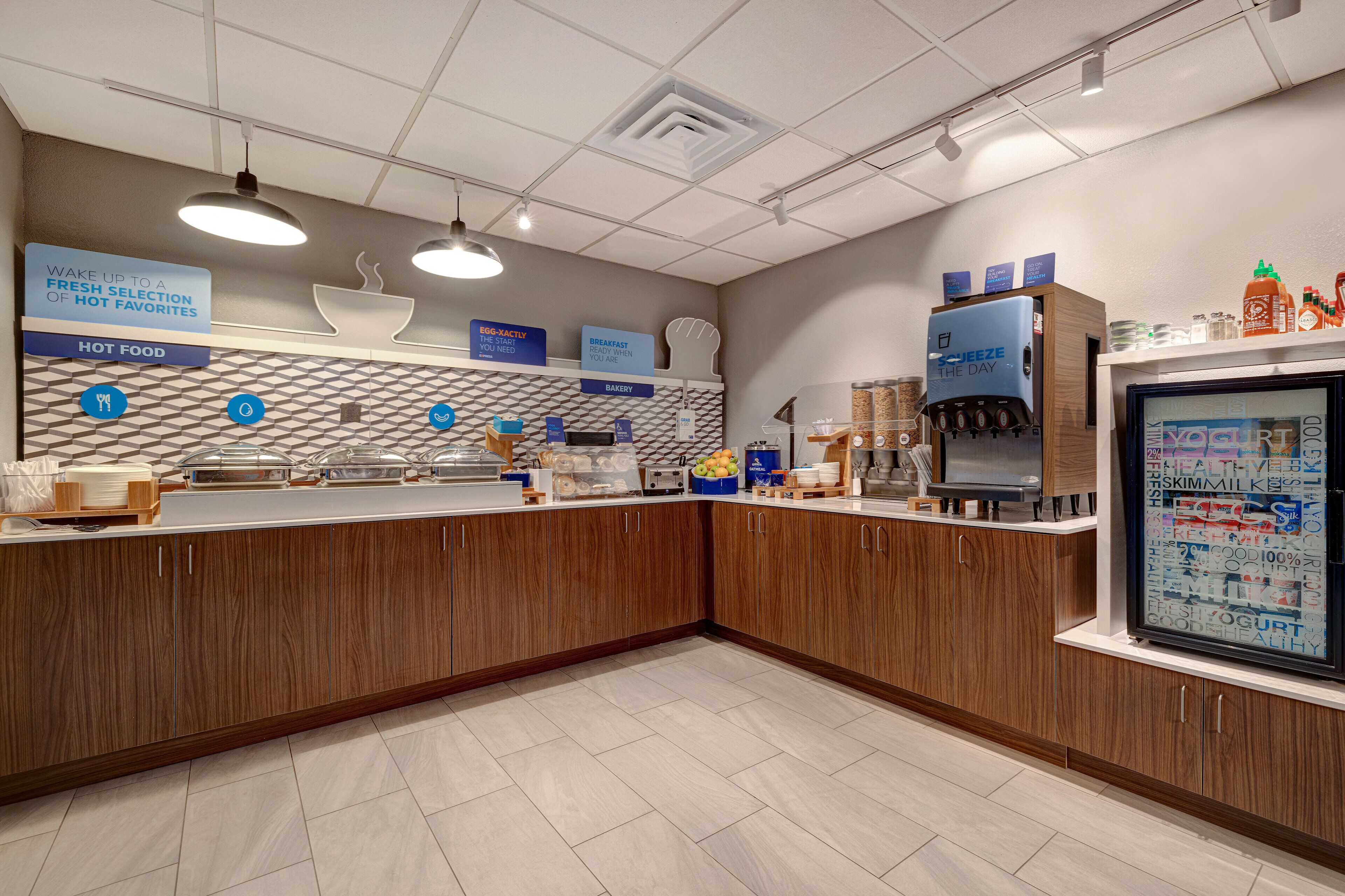 A modern breakfast area with a counter, coffee machine, and refrigerated display.