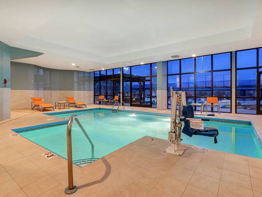 Une piscine intérieure avec des parois en verre transparent, de nombreux fauteuils et un poste de surveillance pour les sauveteurs.