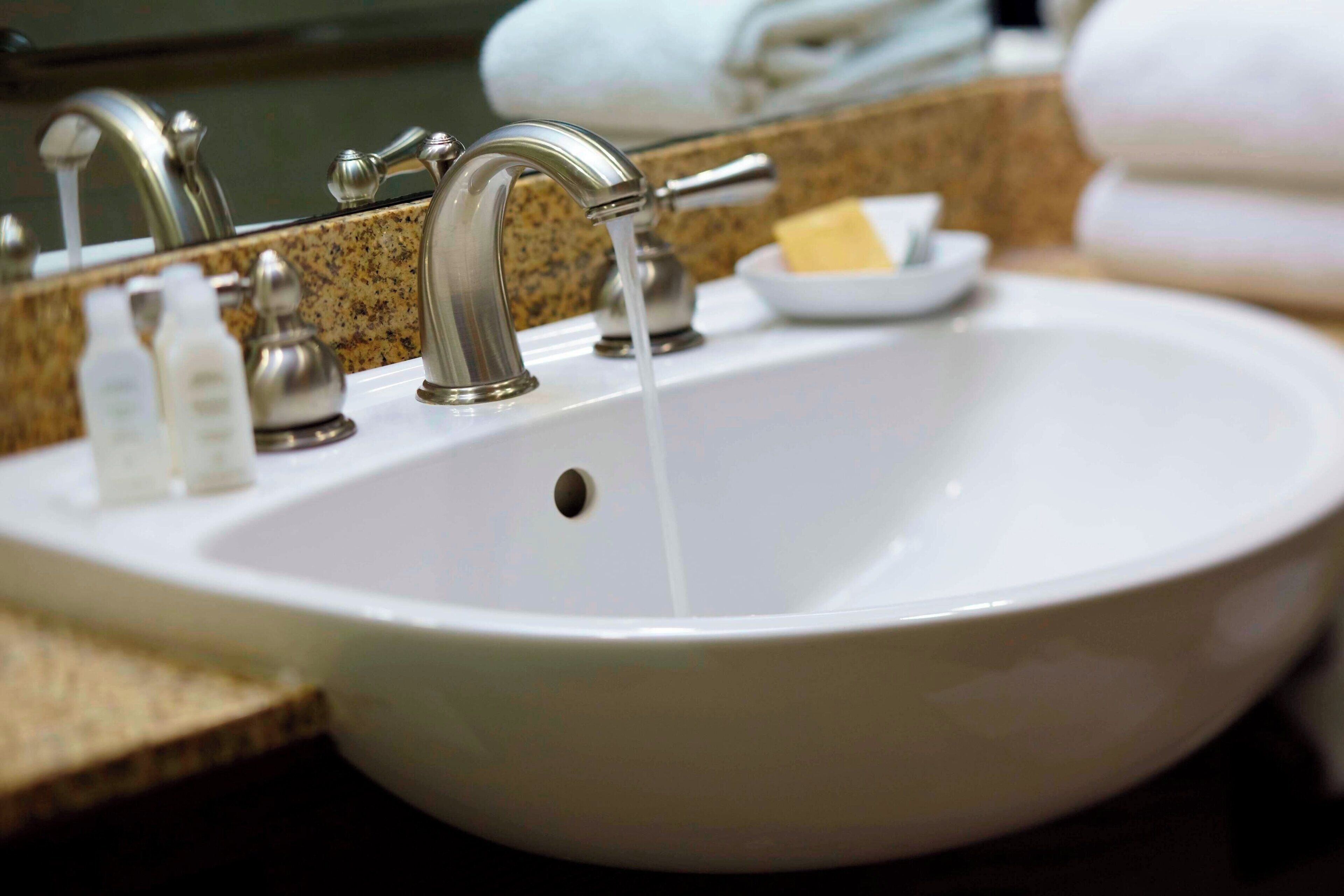 A white bathroom sink with a single faucet, a soap dish, and a mirror above it.