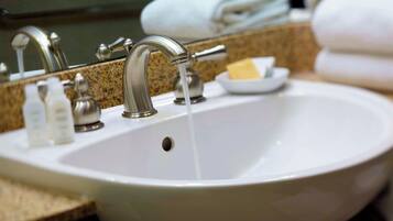 A white bathroom sink with a single faucet, a soap dish, and a mirror above it.