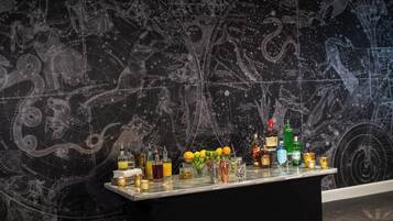 A bar area with a dark, starry map background and a variety of bottles and glasses on the counter.