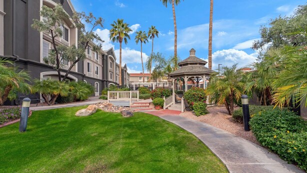 A well-maintained courtyard with a gazebo, palm trees, and a pathway leading to a building with a grey facade. - La Quinta Inn & Suites by Wyndham Phoenix Scottsdale (Scottsdale)