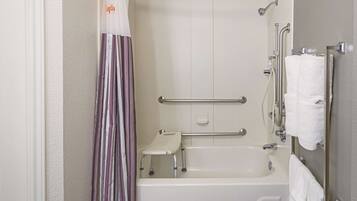 A bathroom with a bathtub, grab bars, a shower curtain, and a towel rack.