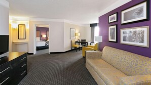 A hotel room with a sofa, a TV, a desk, and a chair. There are framed pictures on the wall. - La Quinta Inn & Suites by Wyndham Phoenix Scottsdale (Scottsdale)