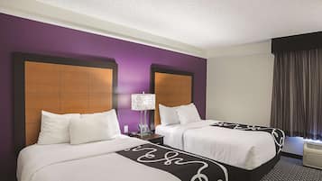 A hotel room with two beds, purple walls, and a ceiling fan.