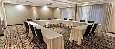 Un salón de conferencias con una mesa larga, sillas y una alfombra estampada.