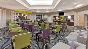 A hotel lobby with multiple seating areas, a reception desk, and a kitchen in the background. - La Quinta Inn & Suites by Wyndham Phoenix Scottsdale (Scottsdale)