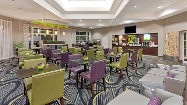 Un hall de hotel con varias zonas de estar, una recepción y una cocina al fondo.