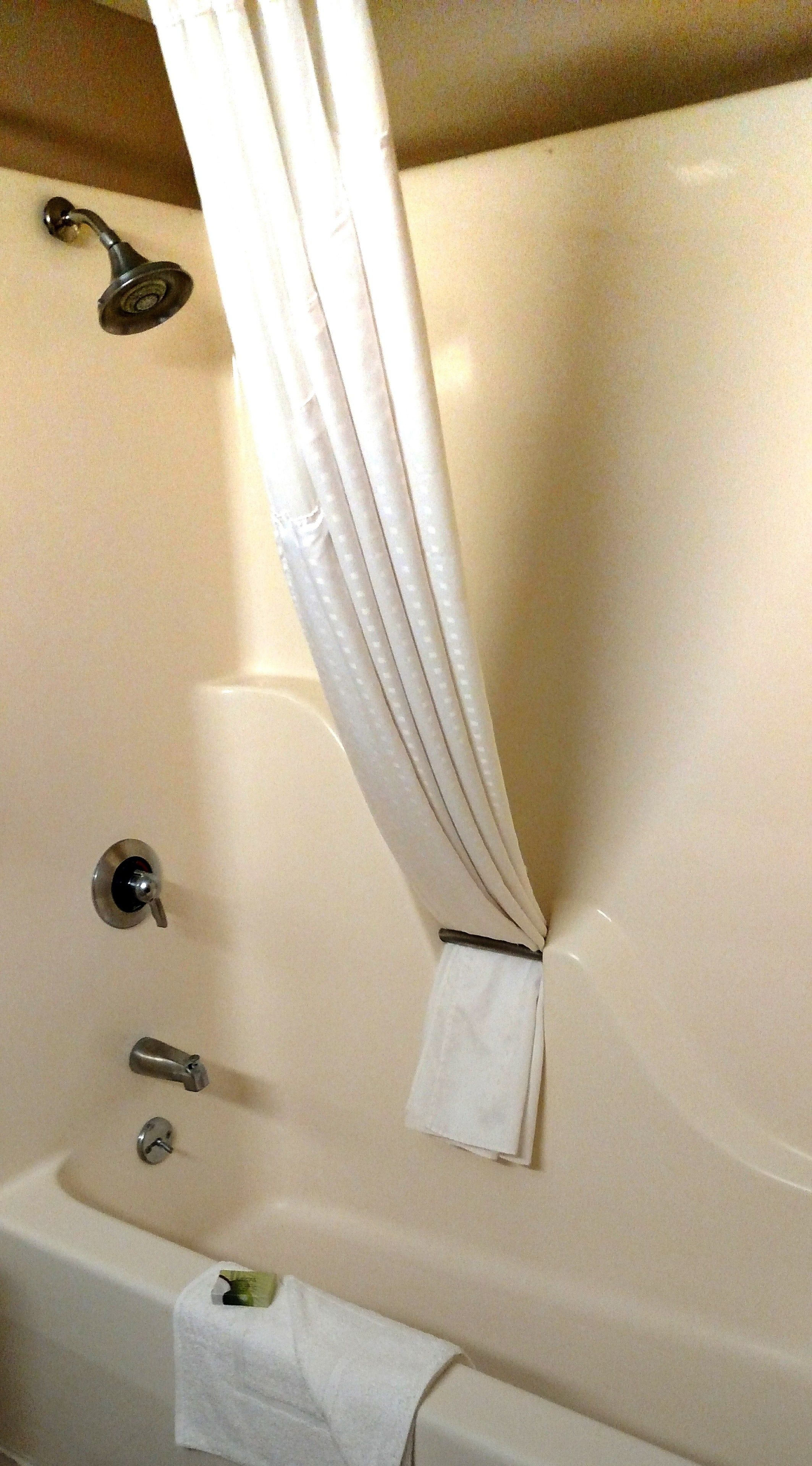 A bathroom with a bathtub, a shower head, and a towel rack.