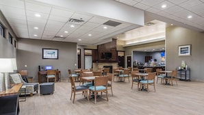A spacious dining area with multiple tables and chairs, a bar area with a television, and a fireplace.