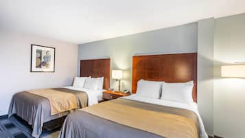 Habitación de hotel con dos camas, una mesita de noche, una lámpara y un cuadro en la pared.