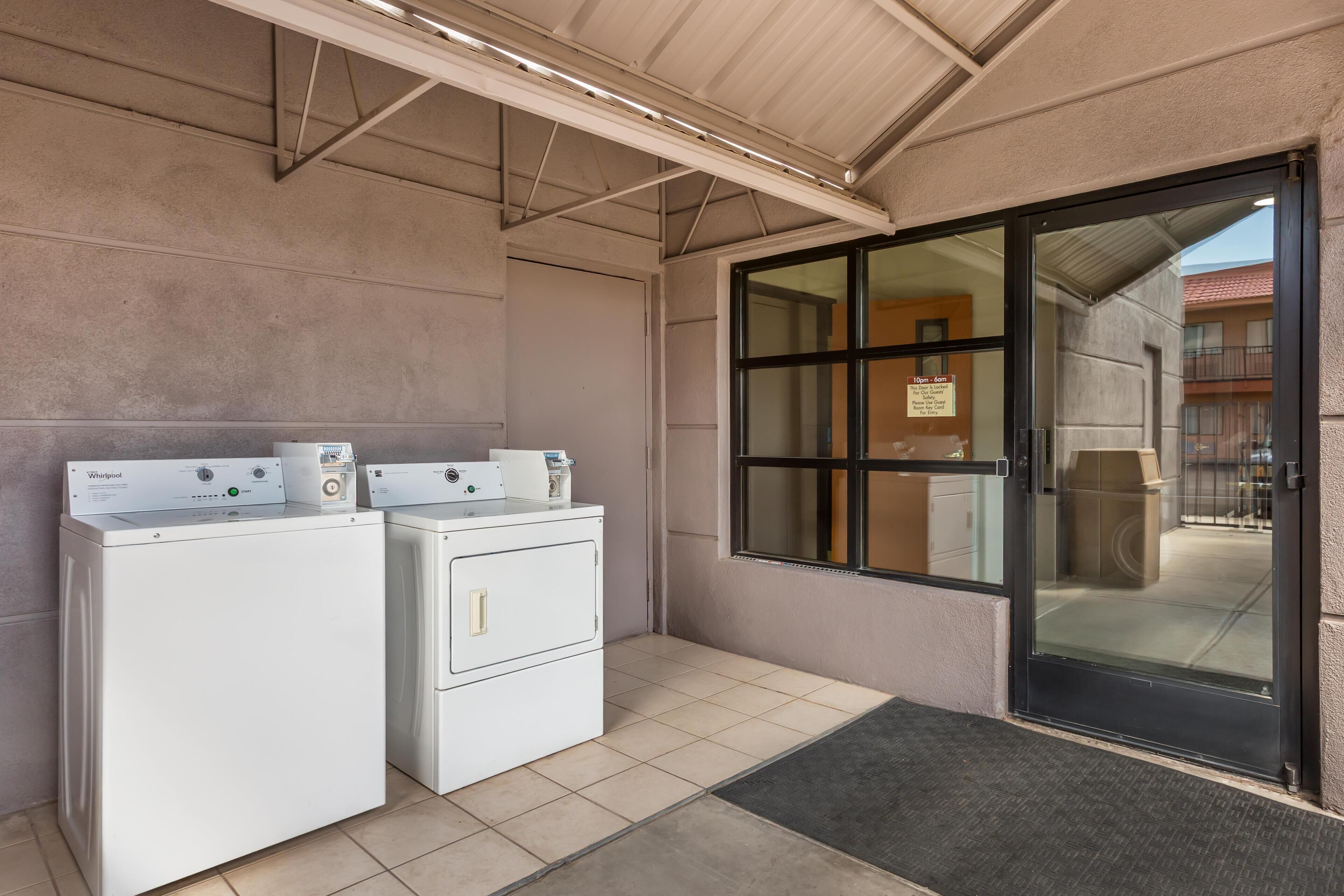 Un área de lavandería con dos lavadoras Whirlpool, piso de baldosas y una puerta que da a un balcón.