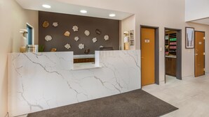 Un espace d’accueil doté d’un comptoir en marbre, d’œuvres d’art décoratives murales et d’un bureau de réception.