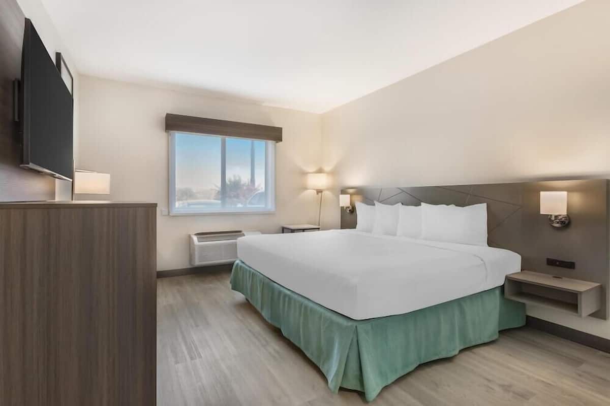 Une chambre d’hôtel avec un grand lit, une télévision, une fenêtre donnant sur un beau paysage et une table de chevet.