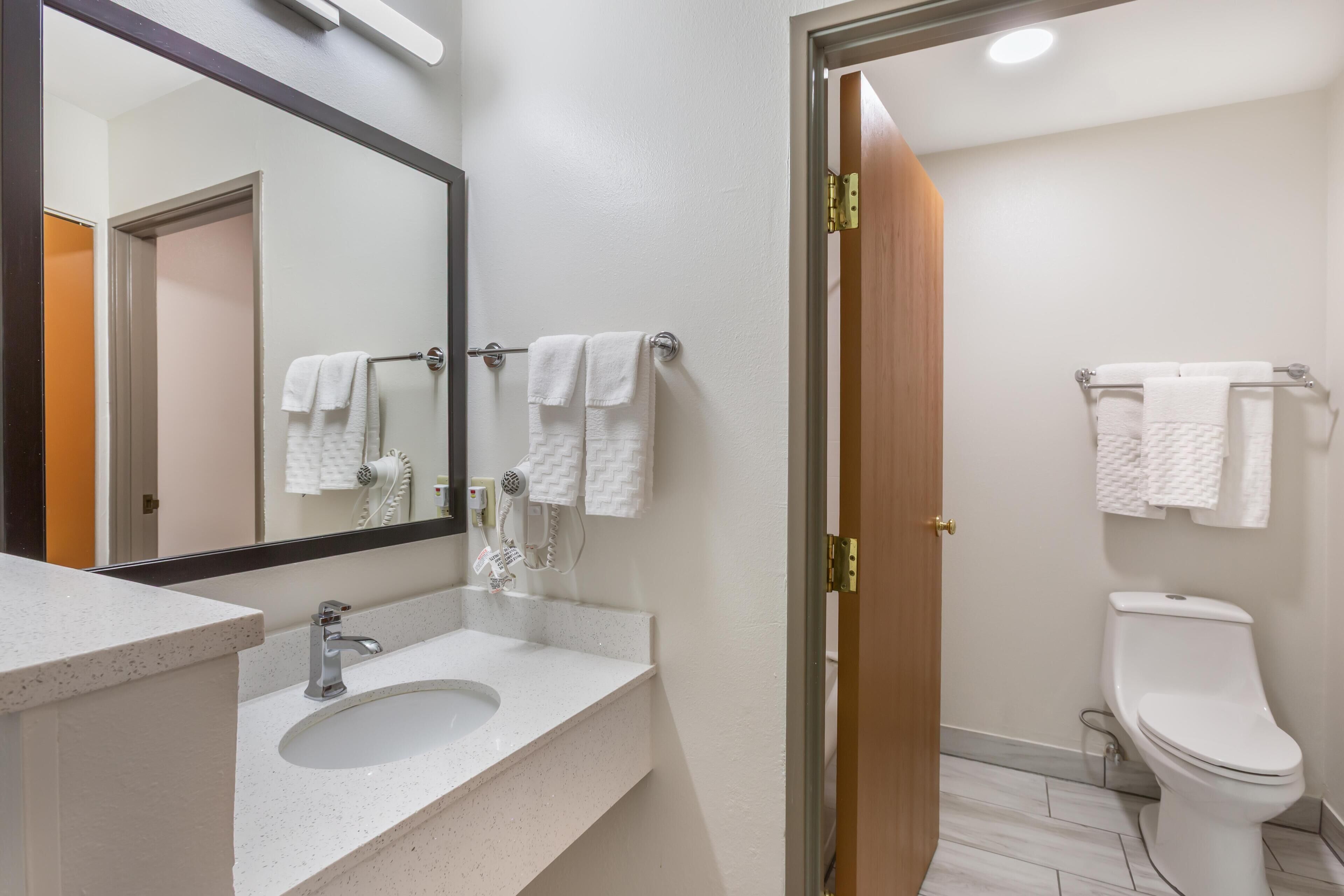 A bathroom with a sink, mirror, towel rack, and toilet.