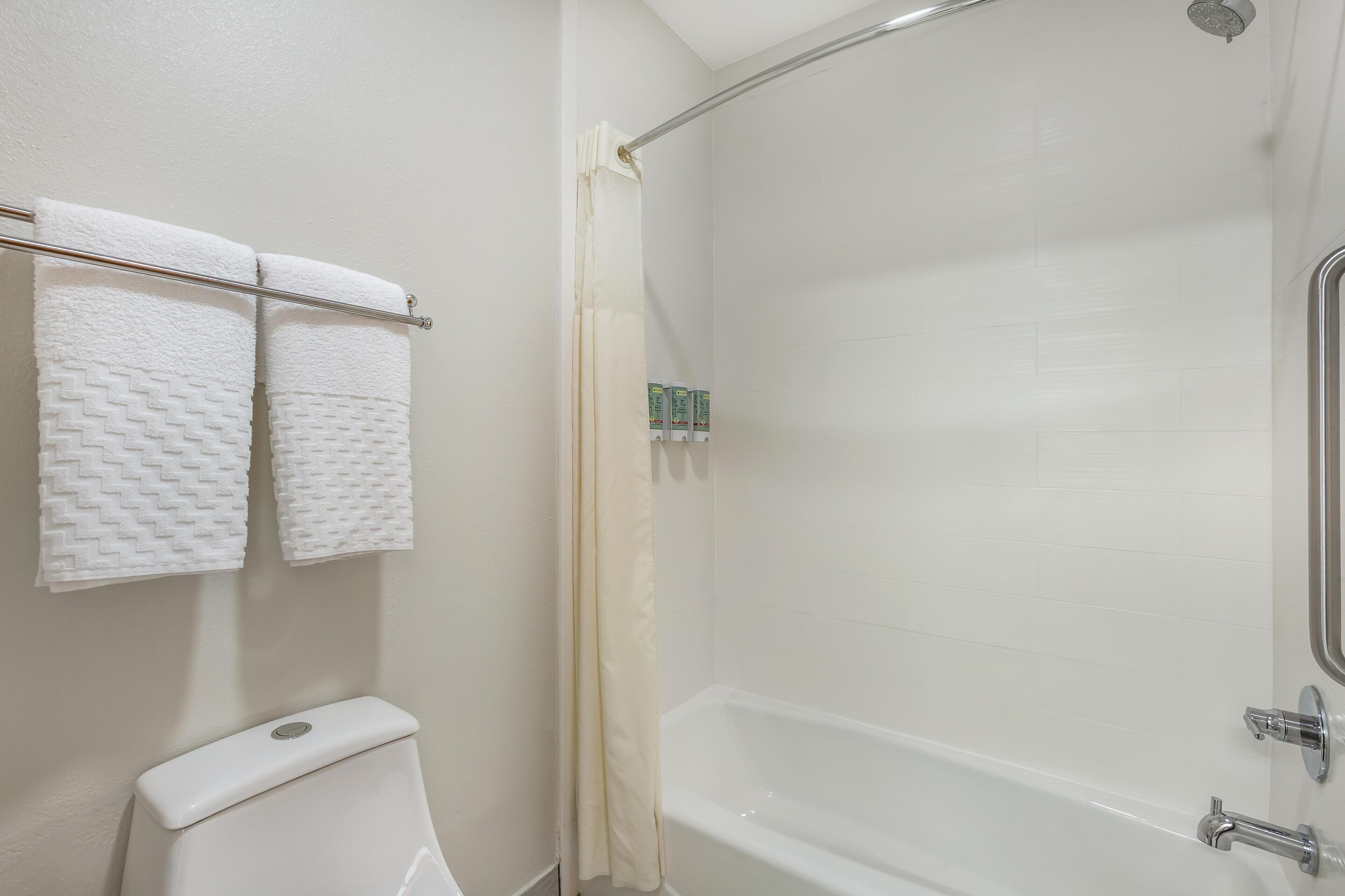A bathroom with a toilet, a bathtub, and two towels hanging on a rack.