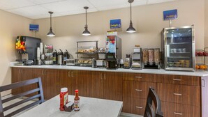 Un espace où l'on peut se servir soi-même pour le petit-déjeuner, comprenant une machine à café, un grille-pain et un présentoir réfrigéré.