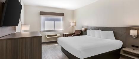 Een moderne hotelkamer met een groot bed, een bureau, een stoel en een flatscreen televisie.