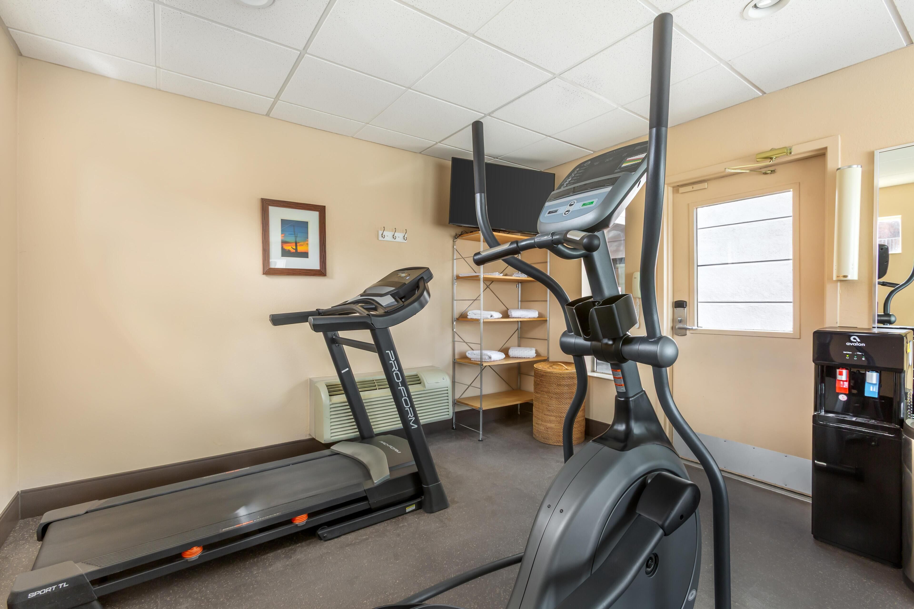 A fitness room with treadmills, an elliptical, and a water dispenser.